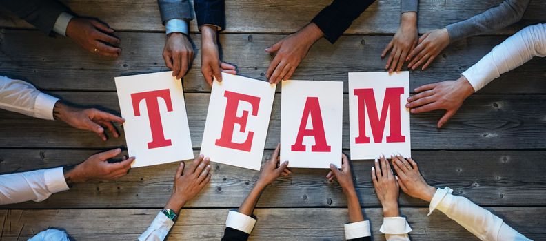 Business people holding TEAM letters printed on paper