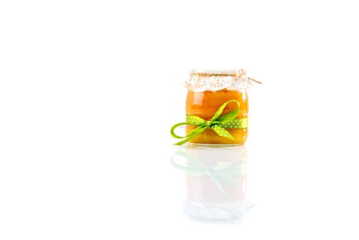 Glass jar with apricot jam isolated on white background.