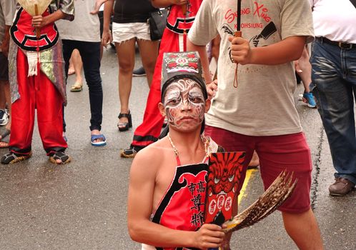 KAOHSIUNG, TAIWAN -- JULY 9, 2016: Male dancers with face painted masks perform during a traditional religious temple ceremony.