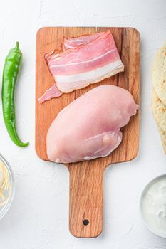 Chicken brest for mexican tacos ingredients on chopping board over white textured backgroundside view