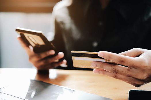 Happy young woman online shopping by credit card payment on mobile smart phone and laptop computer.