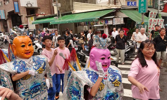 KAOHSIUNG, TAIWAN -- JULY 9, 2016: Male dancers with head covering masks perform during a traditional religious temple ceremony.