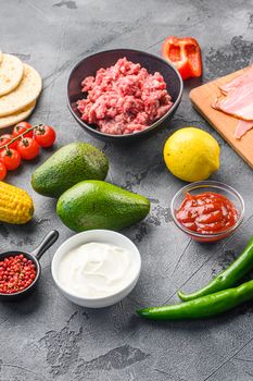 Taco ingredients homemade cooking with vegetables and chicken beef and pork meat, corn, mushrooms on grey background side view