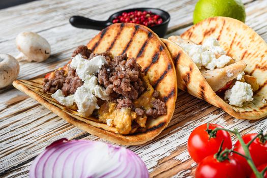 Mexican taco with meat and ingredients, over white textured wooden surface background, side view, selective focus