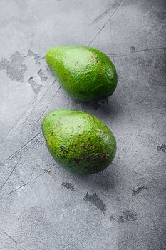Organic avocado over grey textured background, side view