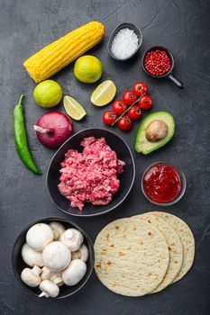 Traditional mexican tortilla with a mix of ingredients, corn, meat, vegetables, salsa, sauce over black textured background, top view