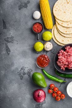 Traditional homemade taco ingredients with meat,salsa, peppers, tomatoes, avocado , corn, tortilla over grey background, top view with space for text