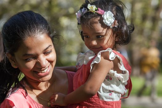 A happy south asian female with two years old girl in spring park