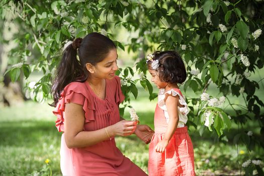 A happy woman in red dress with two years old girl in spring park