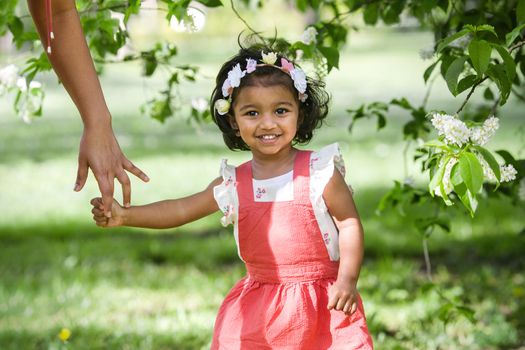 A two years old girl is walking in park in sunny spring day