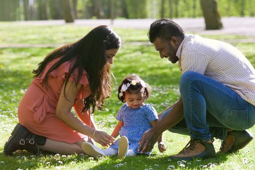 Father and mother are playing with their small daughter in city park