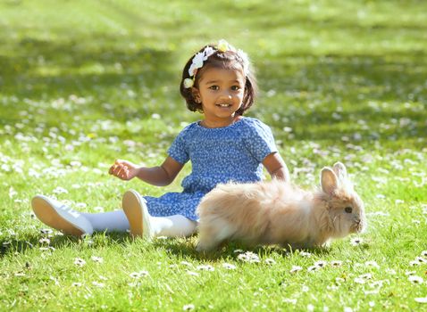 A small Asian girl  with home rabbit on green grass
