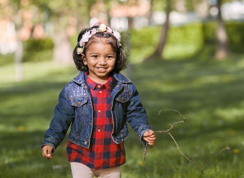 A smiling South Asian girl is playing in city park