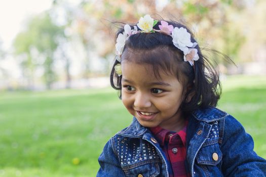 A happy south asian girl is walking in city park