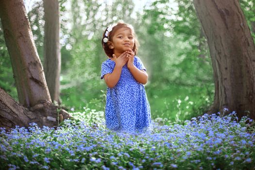a little swarthy girl among the blue flowers in the Park