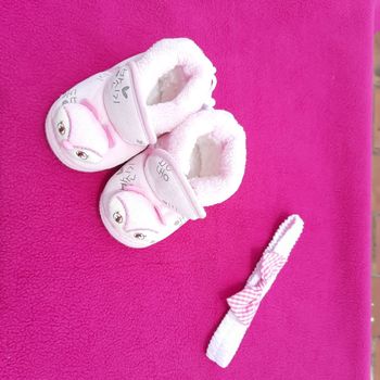Baby shoes placed beautifully in pink background with bow band