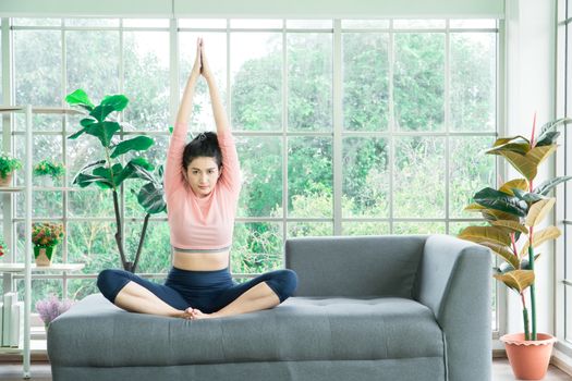 Attractive and healthy woman Asian are exercising Stretching with yoga postures at home helps to balance life.copy space is on the left side of the image For adding text