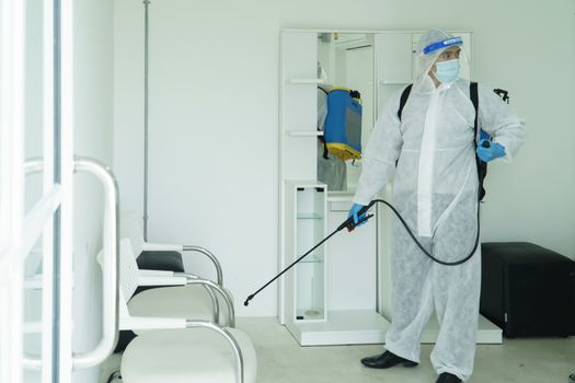 Workers wear protective clothing and wear a mask. Spraying disinfectants for cleaning inside the building. Cleaning service professionals are becoming popular After the spread of coronavirus
