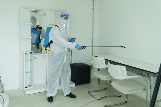 Workers wear protective clothing and wear a mask. Spraying disinfectants for cleaning inside the building. Cleaning service professionals are becoming popular After the spread of coronavirus