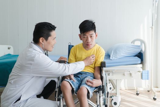 Asian Volunteer Doctors Caring and Helping Rehabilitation of Disabled Boys Stay at the hospital. The boy is crippled, Asian people can't help themselves. Must sit in a wheelchair all the time