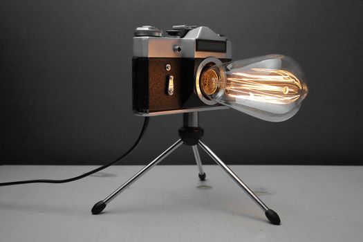 Retro lamp from an old camera with an Edison lamp on a gray background. Concept is a good idea. High quality photo