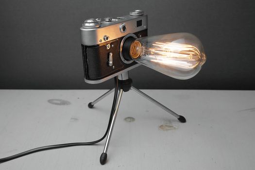 Retro lamp from an old camera with an Edison lamp on a gray background. Concept is a good idea. High quality photo