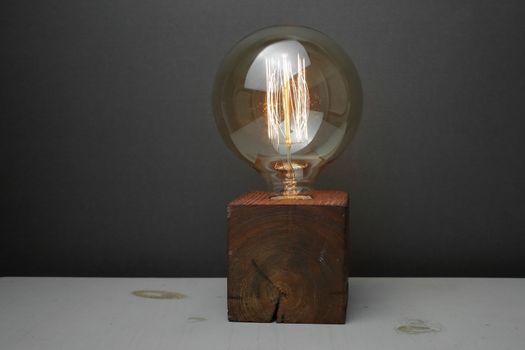 Retro wood lamp with Edison lamp on a gray background. The concept is a good idea. High quality photo