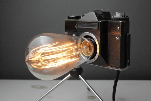 Retro lamp from an old camera with an Edison lamp on a gray background. Concept is a good idea. High quality photo