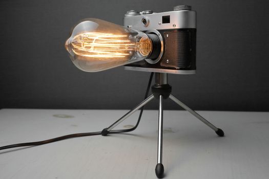 Retro lamp from an old camera with an Edison lamp on a gray background. Concept is a good idea. High quality photo