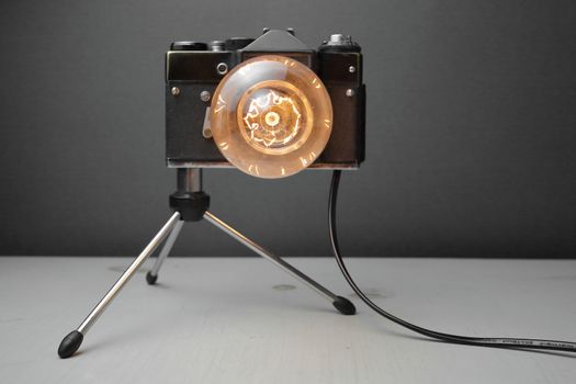 Retro lamp from an old camera with an Edison lamp on a gray background. Concept is a good idea. High quality photo