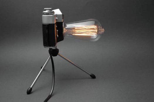 Retro lamp from an old camera with an Edison lamp on a gray background. Concept is a good idea. High quality photo