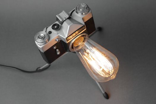 Retro lamp from an old camera with an Edison lamp on a gray background. Concept is a good idea. High quality photo