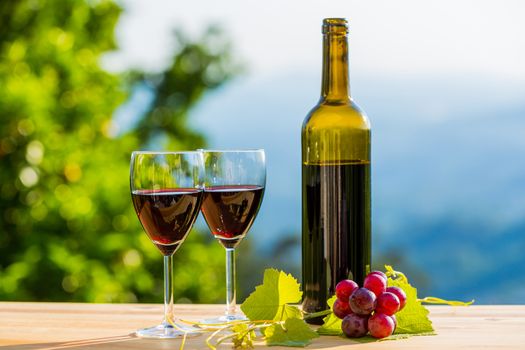 wine bottle and grapes on wooden table, outdoor