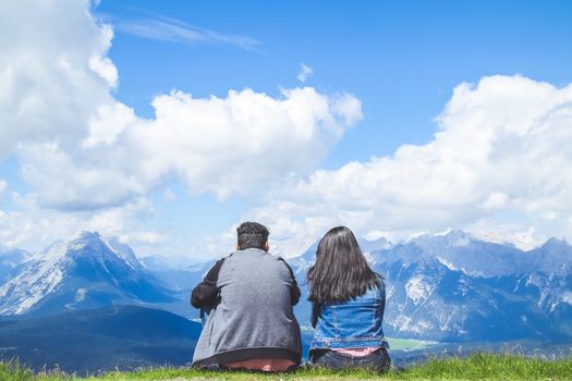 a couple traveller sitting admiring the scenery of the Alps mountains.