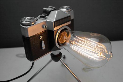 Retro lamp from an old camera with an Edison lamp on a gray background. Concept is a good idea. High quality photo