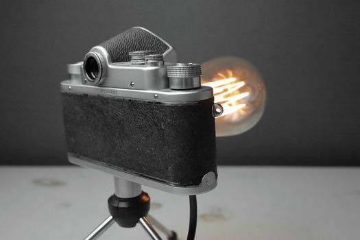 Retro lamp from an old camera with an Edison lamp on a gray background. Concept is a good idea. High quality photo