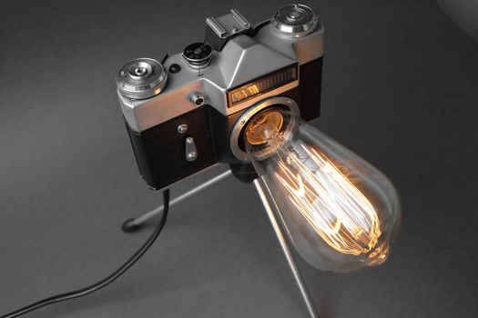 Retro lamp from an old camera with an Edison lamp on a gray background. Concept is a good idea. High quality photo