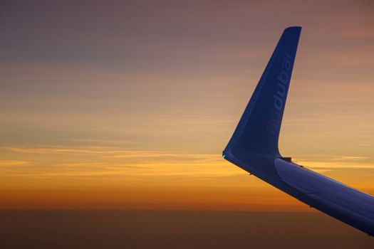 DUBAI, UAE - Circa 2020: Airplane wing while flying with a beautiful colorful sunset. Orange sunset sky. Travel concept.