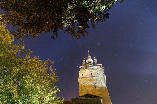 SIGHISOARA, ROMANIA - Circa 2020: Old medieval town night view with starry sky. Beautiful tourist spot in eastern central Europe. Famous old medieval tower in Sighisoara Romania. Calm night concept