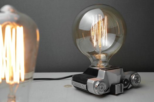 Retro lamp from an old camera with an Edison lamp on a gray background. Concept is a good idea. High quality photo