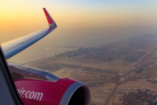 DUBAI, UAE - CIRCA 2020: View of Dubai skyline from an airplane during a colorful sunset. View of Persian Golf and Dubai skyscrapers.