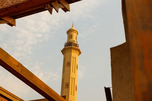 A mosque minaret against clear blue sky with scattered clouds on sunset. Copy space. Eid Ramadan spirituality concept