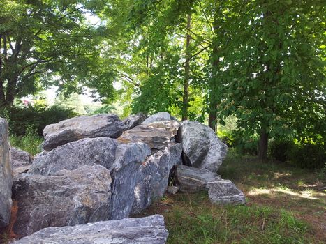 Large stones or rock settled in between green trees in a public park