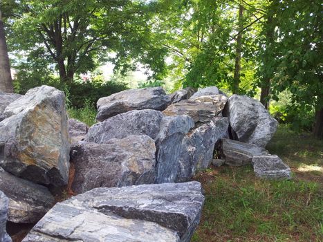 Large stones or rock settled in between green trees in a public park