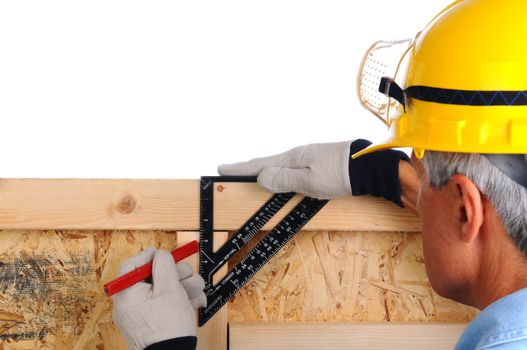 Closeup of a carpenter using a framing square to mark lines on the studs of a wall he is building. The man wearing a work shirt, gloves and a hard hat. Shallow depth of field with the focus on the hand and tool.
