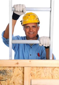 Closeup of  a construction worker climbing a ladder isolated over white. The man wearing a work shirt, gloves and a hard hat is partially hidden behind a wood framed wall. Vertical Format.