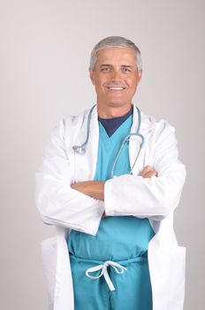 Middle Aged  Doctor in Scrubs and Lab Coat with his arms folded - vertical on Gray Background