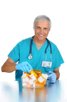 Smiling middle aged doctor choosing a prescription bottle from a bin of bottles. Vertical format isolated on white.
