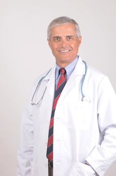 Smiling Middle Aged  Male Doctor in Lab Coat with Stethoscope - gray background