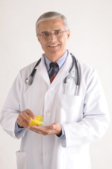 Middle Aged Doctor in Labcoat Pouring Pills into His Hand vertical composition on gray background